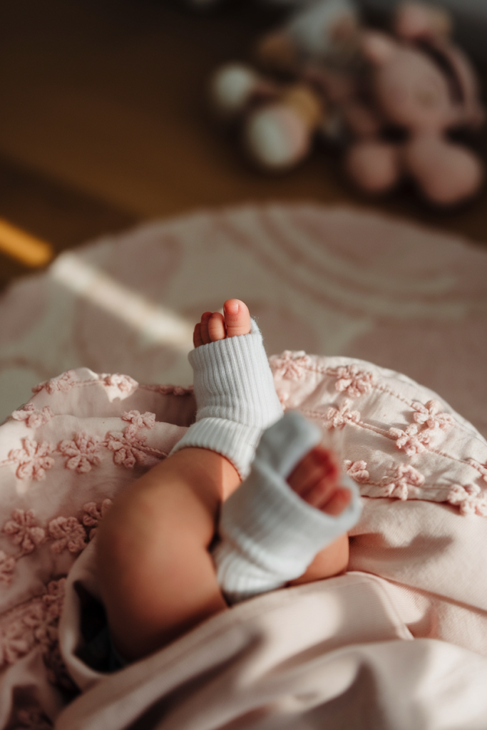 A close-up of a pair of tiny newborn baby feet wrapped in a soft blanket, with a small toy or accessory placed nearby