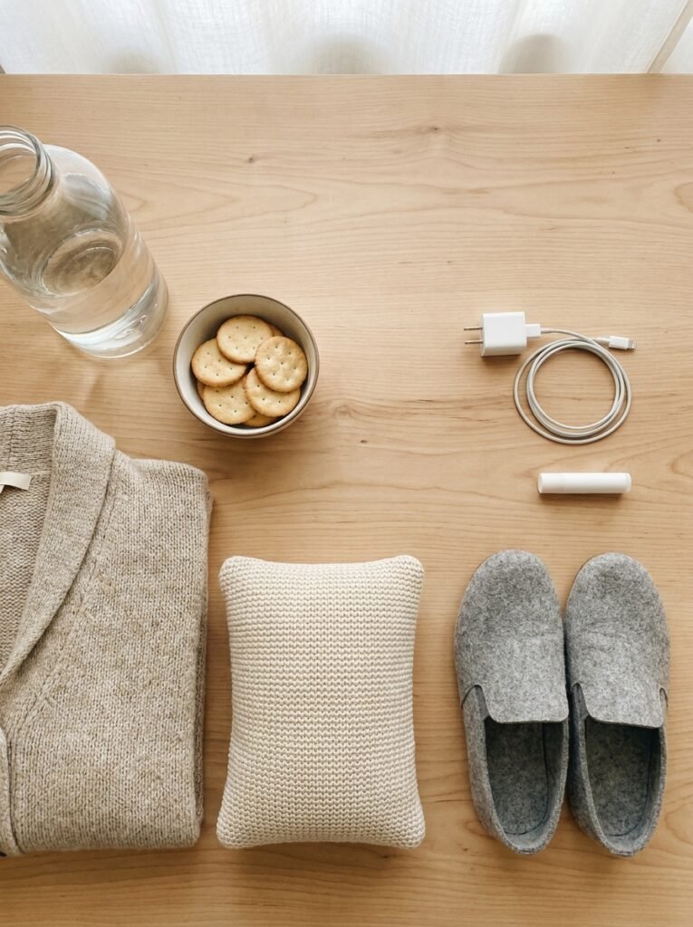 Water bottle, crackers, small pillow, lip balm and cardigan arranged on an office desk